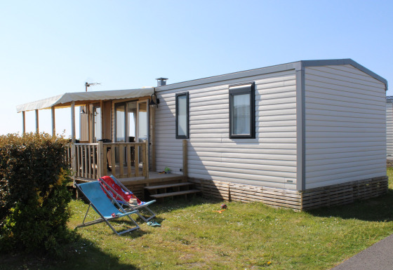 Udendørsbillede af Mobile home Premium HORIZON med overdækket terrasse og liggestole i solen.