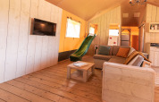 Interieur van safaritent ‘De Medley’ bij Glamping de Bosweide in Nederland, met bank en glijbaan.
