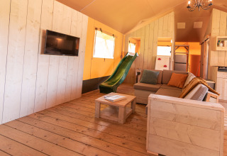 Interieur van safaritent ‘De Medley’ bij Glamping de Bosweide in Nederland, met bank en glijbaan.