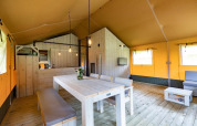 Innenansicht eines Safari-Zeltes bei Glamping de Bosweide in den Niederlanden mit Holzmöbeln.