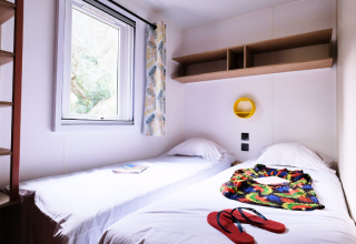Habitación luminosa en Mobile Home Premium en el camping La Vallée Heureuse, Francia, con dos camas y ventana.