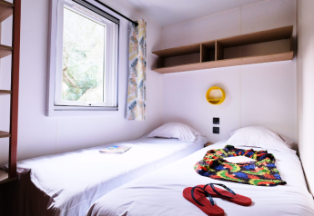 Helles Zimmer im Mobile Home Premium auf dem Campingplatz La Vallée Heureuse mit zwei Einzelbetten und Fenster.