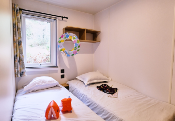 Schlafzimmer im Mobile Home Premium auf dem Campingplatz La Vallée Heureuse in Frankreich mit zwei Betten.
