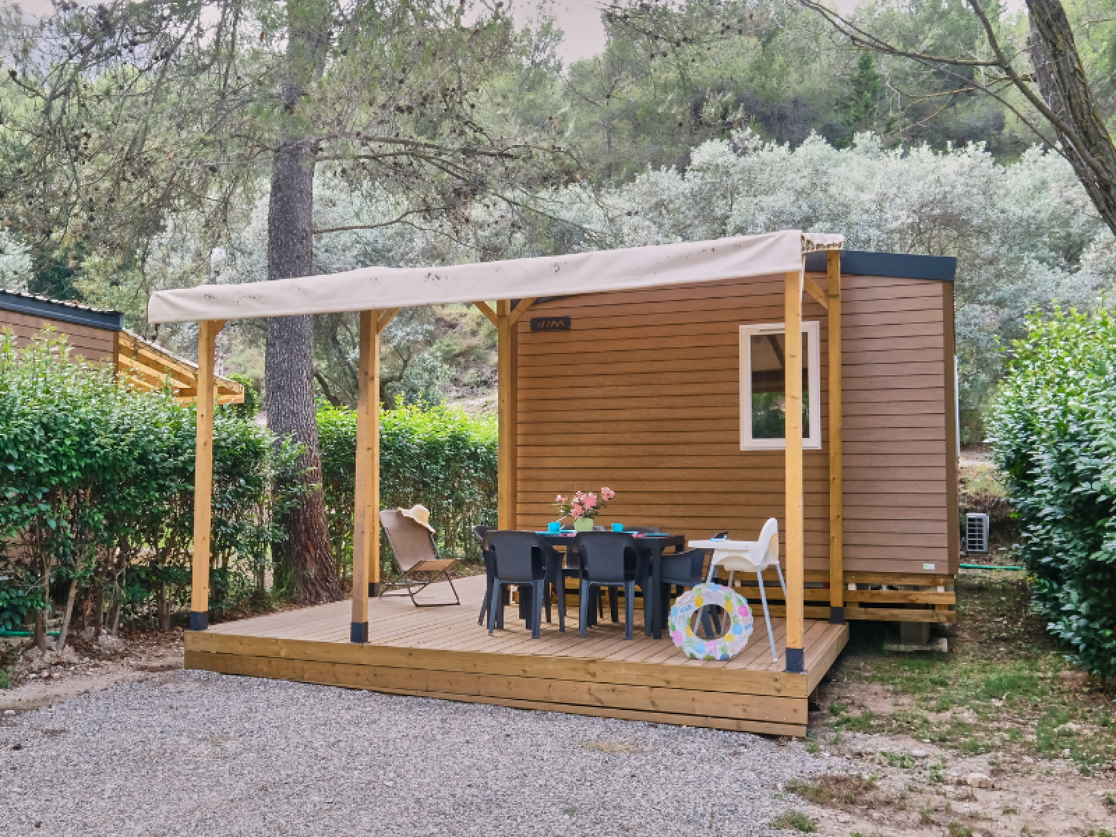 Mobile Home Premium met houten terras, buitentafel en stoelen, omgeven door groen in een rustige omgeving.