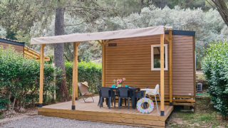 Mobile Home Premium met houten terras, buitentafel en stoelen, omgeven door natuur en groen.