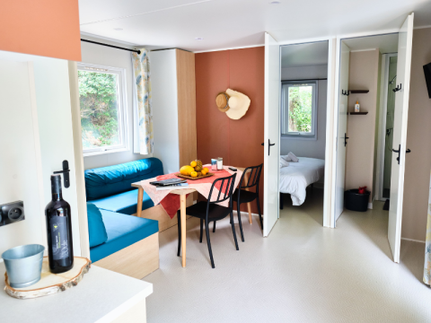 Heller, moderner Wohnbereich eines Mobilheims mit Esstisch und Zugang zum Schlafzimmer in La Vallée Heureuse.