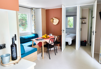 Heller, moderner Wohnbereich eines Mobilheims mit Esstisch und Zugang zum Schlafzimmer in La Vallée Heureuse.