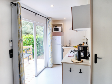 Cocina de casa móvil moderna con puertas correderas hacia la terraza y jardín en Camping La Vallée Heureuse.