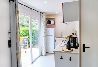 Cocina de casa móvil moderna con puertas correderas hacia la terraza y jardín en Camping La Vallée Heureuse.