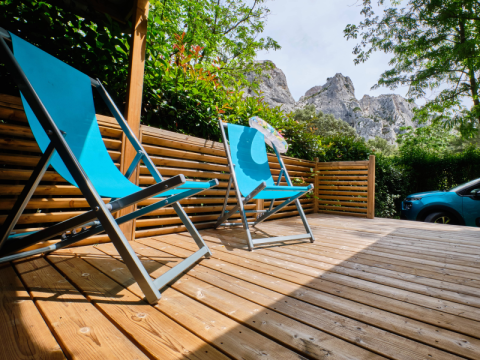 Holzterrasse mit blauen Liegestühlen am Mobile Home 'Premium Large' auf Campingplatz La Vallée Heureuse, Frankreich.