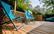 Terrasse en bois avec chaises longues bleues au mobil-home « Premium Large » du Camping La Vallée Heureuse, France.