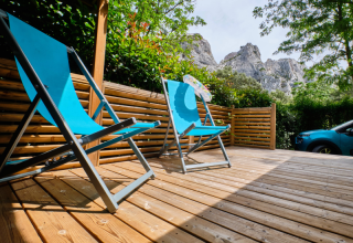 Terrazza in legno con sedie sdraio blu nella casa mobile 'Premium Large' al campeggio La Vallée Heureuse, Francia.