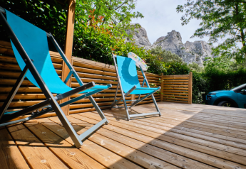 Holzterrasse mit blauen Liegestühlen am Mobile Home 'Premium Large' auf Campingplatz La Vallée Heureuse, Frankreich.