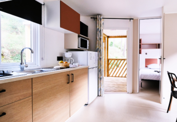 Modernes Mobilheim-Küche mit Holzmöbeln, Blick auf Schlafzimmer und Terrasse auf Campingplatz La Vallée Heureuse.