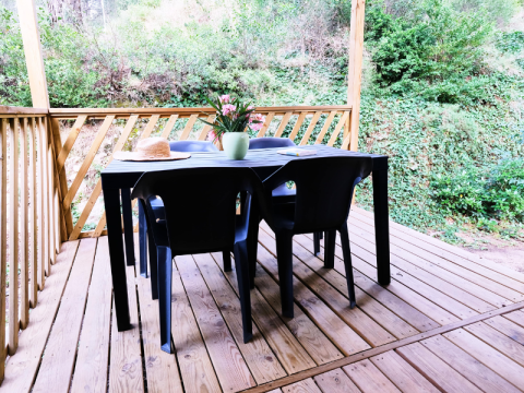 Udendørs terrasse med trædæk, sort bord og stole, samt planter, set ved Mobile Home Premium i Frankrig.