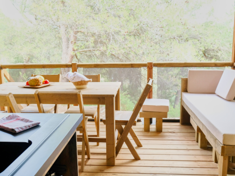 Houten terras met eethoek in een Premium Lodge safaritent op Camping La Vallée Heureuse in Frankrijk.
