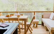 Terraza de madera en tienda safari Premium Lodge en el camping La Vallée Heureuse, Francia, con frutas.