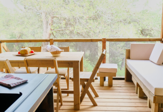 Zona pranzo in terrazza di legno nel safari tent Premium Lodge al Campeggio La Vallée Heureuse, Francia.