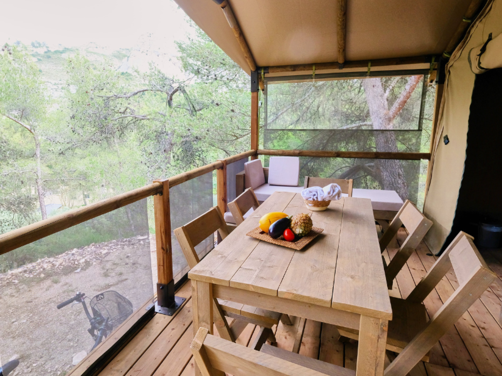 Houten tafel en stoelen op het terras van de Premium Lodge safaritent bij Camping La Vallée Heureuse, Frankrijk.