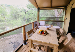 Tavolo e sedie in legno sulla terrazza della tenda safari Premium Lodge al campeggio La Vallée Heureuse, Francia.