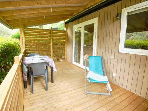 Træterrasse med spisebord, stole og liggestol ved Mobile Home Premium, Campsite La Vallée Heureuse, Frankrig
