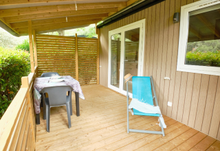 Terraza de madera con mesa, sillas y tumbona en Mobile Home Premium, Camping La Vallée Heureuse, Francia