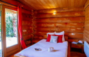 Accogliente camera da letto in legno in una casa nella natura, letto matrimoniale e vista sul giardino.