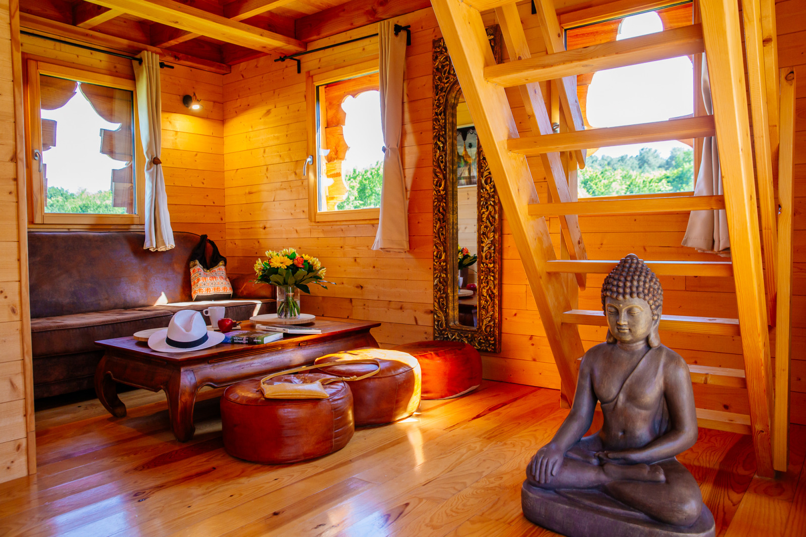 Houten boomhutinterieur met Boeddhabeeld bij Log cabin «Temple perché» op Domaine EcÔtelia, Frankrijk.