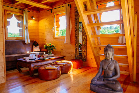 Sfeervol interieur van houten boomhut met Boeddhabeeld, Log cabin «Temple perché», Domaine EcÔtelia, Frankrijk.