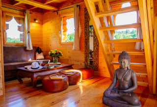 Cozy wooden tree house interior with Buddha statue at Log cabin «Temple perché», Domaine EcÔtelia, France.
