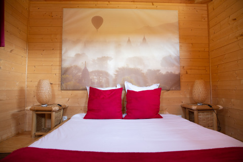 Innenansicht einer Baumhaus-Hütte im Domaine EcÔtelia, Frankreich, mit Doppelbett und Holzwänden.