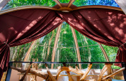 Vista interior de la tienda Bubbel en Domaine EcÔtelia, Francia, con grandes ventanales y bosque exterior.