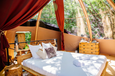 Tente safari Bubbel au Domaine EcÔtelia en France, avec lit confortable et vue sur la forêt environnante.