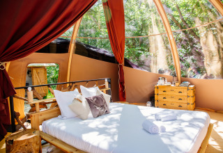 Tente safari Bubbel au Domaine EcÔtelia en France, avec lit confortable et vue sur la forêt environnante.
