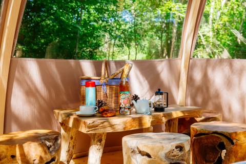 Intérieur de tente safari rustique au Domaine EcÔtelia, France, avec meubles en bois et petit-déjeuner.
