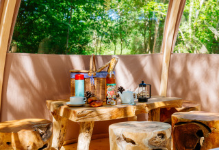 Intérieur de tente safari rustique au Domaine EcÔtelia, France, avec meubles en bois et petit-déjeuner.