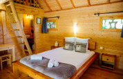 Gemütliches Schlafzimmer im Baumhaus «Palombière» im Domaine EcÔtelia, Frankreich, mit natürlichen Holzwänden.