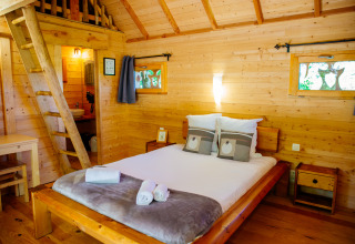 Chambre chaleureuse de la cabane dans les arbres «Palombière» au Domaine EcÔtelia, France, toute en bois naturel.