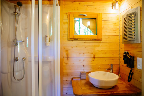 Badeværelse i træhus med bruser, håndvask og vindue på Treehouse Palombière, Domaine EcÔtelia, Frankrig.