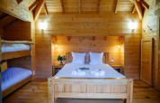 Dormitorio de casa del árbol en Domaine EcÔtelia, Francia, con cama doble, literas y decoración de madera.