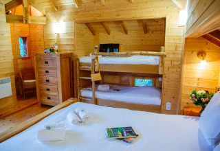 Vue intérieure de la cabane «Château» au Domaine EcÔtelia en France, avec lits superposés et lit double.