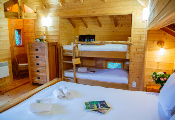 Interior view of Treehouse «Château» at Domaine EcÔtelia in France, featuring bunk beds and a double bed.