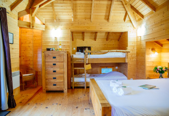 Cozy wooden interior of Treehouse «Château» at Domaine EcÔtelia in France, featuring bunk and double beds.