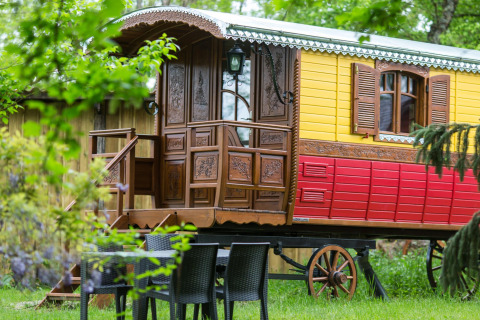 Bunte Zigeunerwagenhütte im Grünen bei Domaine EcÔtelia, Frankreich. Sitzgruppe im Vordergrund.