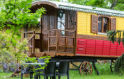Carrozza zingara colorata al Domaine EcÔtelia in Francia, tavolo e sedie da esterno in primo piano.