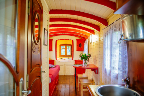 Gemütliches, farbenfrohes Wageninnere der Gypsy wagon Hütte im Domaine EcÔtelia, Frankreich, mit Holzwänden.