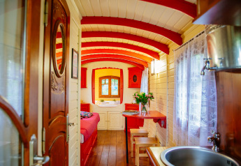 Gemütliches, farbenfrohes Wageninnere der Gypsy wagon Hütte im Domaine EcÔtelia, Frankreich, mit Holzwänden.