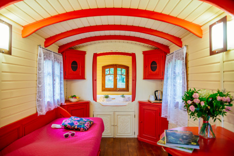 Binnenaanzicht van de kleurrijke Gypsy wagon-hut bij Domaine EcÔtelia in Frankrijk, met rood-witte accenten.