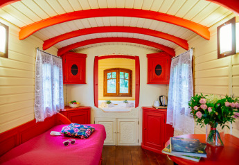 Vista interior de la colorida cabaña Gypsy wagon en Domaine EcÔtelia, Francia, con decoración roja y blanca.