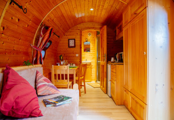 Knus houten hutinterieur met bank, eettafel, keuken en warm natuurlijk licht, sfeervol en gezellig.
